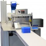 Cut to length solution with unwinds and feeds release liners to be affixed to both sides of an extruded material